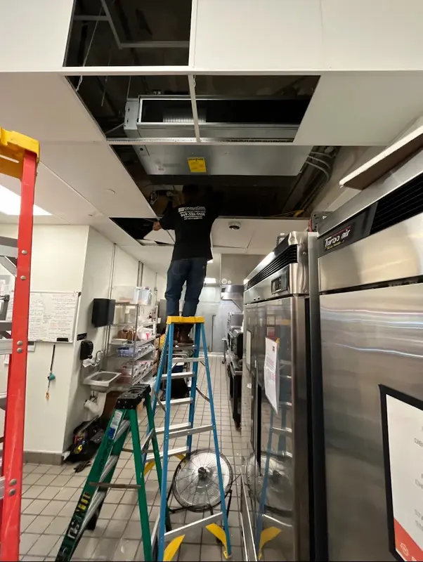 Technician servicing HVAC system in commercial kitchen