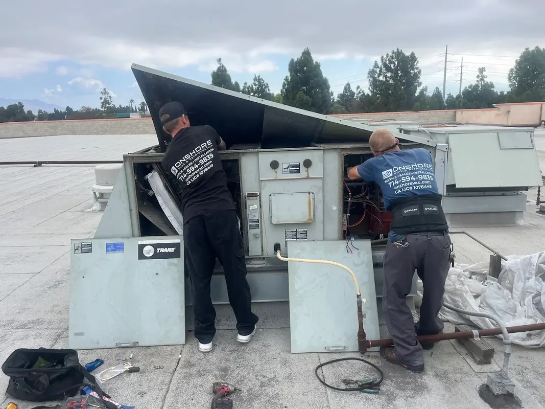 Two Onshore technicians servicing a Trane rooftop unit